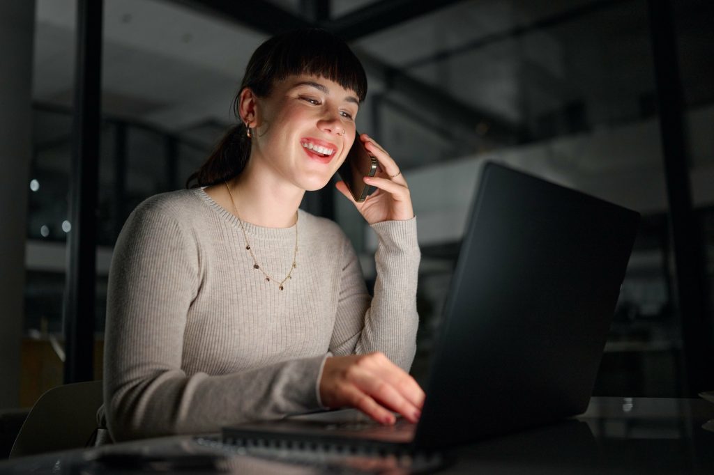 Phone call, laptop and business woman talking, chatting or speaking to contact at night. Dark offic