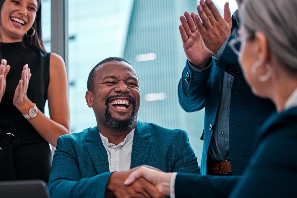 We cant wait to see whaqt you do. Shot of coworkers shaking hands in a boardroom.